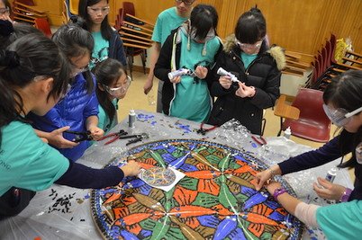 Participants assembling the woodcut Circle Limit III by M.C. Escher using mosaic tiles